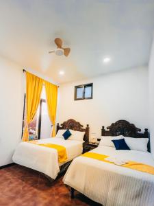- deux lits dans une chambre jaune et blanche dans l'établissement Hotel Villa Luna, à San Juan La Laguna