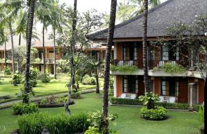 a resort with palm trees in front of it at Nattaya at the Jayakarta Bali in Seminyak