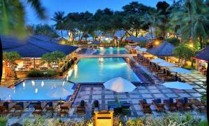 a large swimming pool with chairs and umbrellas at Nattaya at the Jayakarta Bali in Seminyak