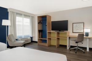 a hotel room with a bed and a desk with a television at Spark By Hilton Wilmington in Wilmington