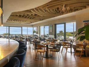 Un comedor con mesas y sillas y ventanas. en SO/ Sotogrande Spa & Golf Resort Hotel, en Sotogrande