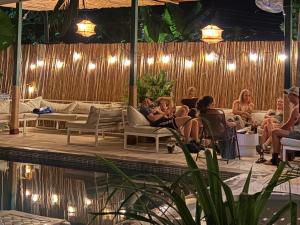 Un gruppo di persone sedute intorno alla piscina a una festa di Dos Palmas a El Sunzal