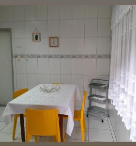 un tavolo bianco con sedie gialle in una stanza con una parete piastrellata bianca di Flat luxo e tranquilidade a Volta Redonda