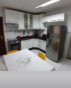 una cucina con tavolo e frigorifero in acciaio inox di Flat luxo e tranquilidade a Volta Redonda