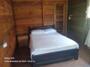 Una cama pequeña en una habitación con paredes de madera. en Chema, en Mocoa