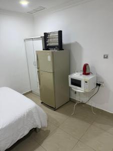 Una habitación con una cama, un microondas y una computadora en un refrigerador. en ماي سويت, en Kuwait