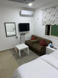 Una sala de estar con un sofá y un televisor. en ماي سويت, en Kuwait