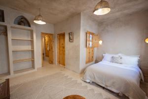 a bedroom with a white bed and two windows at Riad le myrath in Essaouira