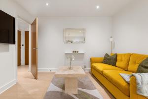 a living room with a yellow couch and a table at Khayat Homes - The Ford in Chelmsford