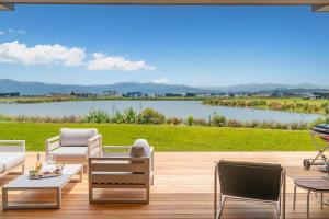 a patio with chairs and tables and a view of a lake at Lakeside Retreat Matarangi - Deluxe Home with Sleep-out in Whitianga
