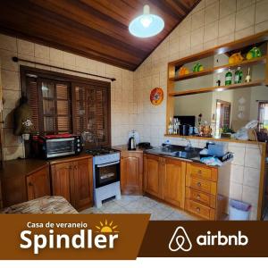 a kitchen with wooden cabinets and a stove top oven at Spindler summer house in Tramandaí