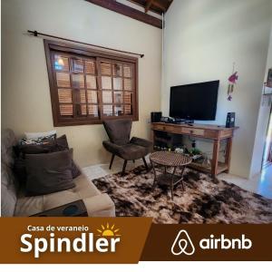a living room with a couch and a desk with a television at Spindler summer house in Tramandaí