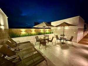 a patio with tables and chairs and umbrellas at night at Hotel Sheik Business in Rio de Janeiro