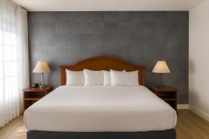 Un dormitorio con una gran cama blanca con dos lámparas. en Granada Inn, en Santa Clara