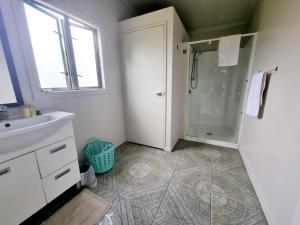 een badkamer met een douche en een wastafel bij Natura Nikao Beachside 3BM Villa in Avarua +22 foto's