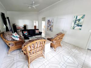 een woonkamer met rieten stoelen en een bank bij Natura Nikao Beachside 3BM Villa in Avarua