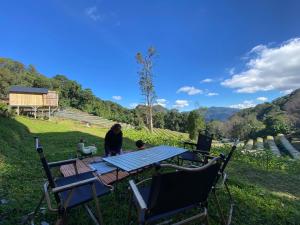 ม่านป่ามองเขาเฮ้าส์ في Ban Sop Mae Klang: امرأة تجلس على طاولة نزهة في العشب