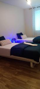 two beds in a room with purple lighting at Tapulikaupunki Apartment Helsinki in Helsinki