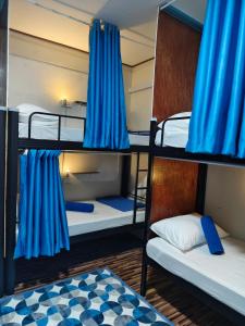 a room with three bunk beds with blue curtains at Anchor Point Hostel and Cafe in Pulau Langkawi