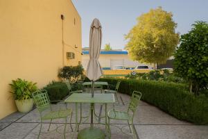 un patio con una mesa con sombrilla y sillas en Granada Inn, en Santa Clara