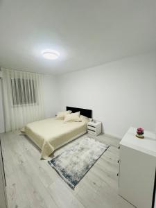 a white bedroom with a bed and a rug at City View Apartment in Mitrovicë