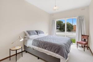 ein weißes Schlafzimmer mit einem Bett und einem Fenster in der Unterkunft Beach Street in Queenscliff