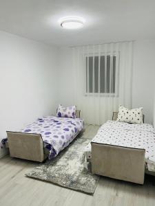 two beds in a room with white walls and wooden floors at City View Apartment in Mitrovicë +4 photos