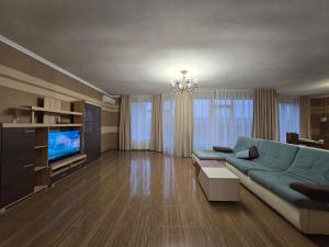 een woonkamer met een blauwe bank en een televisie bij Royal Residence Uzhhorod in Oezjhorod