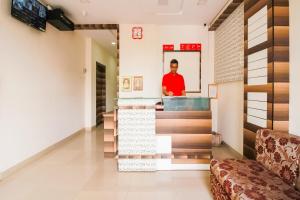 a man in a red shirt standing in a room at Hotel O Unique Inn in Dhule