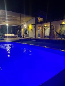 uma grande piscina azul à noite com uma casa em Casa Marea a 300 M do mar - 10 min de Serra Grande em Ilhéus