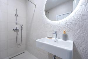 ein weißes Badezimmer mit Waschbecken und Spiegel in der Unterkunft Quince Apartments in Podgorica + 20 Fotos