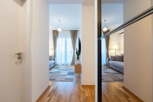 einen Flur, der zu einem Wohnzimmer mit einem Sofa führt in der Unterkunft Quince Apartments in Podgorica