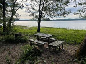 a picnic table and benches in front of a lake at Old Hospital & Sauna at the Beach in Pargas