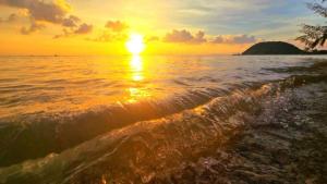 un coucher de soleil sur l'océan avec une vague dans l'établissement Green Heaven Bungalows, à Nathon Bay