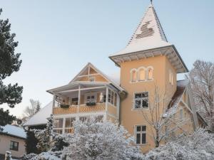 une grande maison avec une tourelle dans la neige dans l'établissement Villa Charlotte, à Bad Suderode