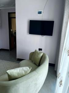 a white couch in a living room with a television on a wall at The Cozy Home Apartment in Fort Portal