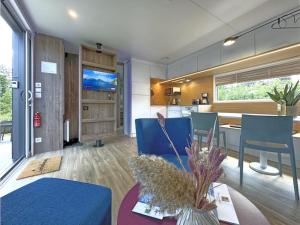 a living room and kitchen with blue chairs and a table at Feriendorf Seeblick - Tiny Chalet Nr 6 in Neunburg vorm Wald