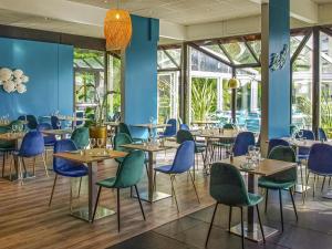 Un restaurante con paredes azules, mesas y sillas. en Novotel Marseille Est Porte d'Aubagne, en Marsella
