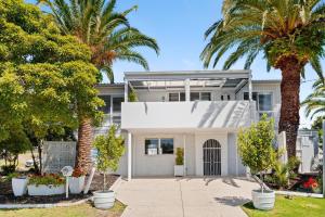 una casa con palmeras delante en SANTORINI BEACH HOUSE SAFETY BEACH, en Safety Beach