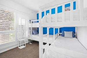 1 dormitorio con literas blancas y paredes azules en SANTORINI BEACH HOUSE SAFETY BEACH, en Safety Beach 25 fotos más