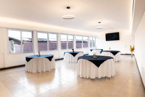 Una habitación con cuatro mesas con manteles blancos y azules. en Los Faroles Zona 3, en Cobán