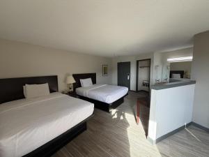 a hotel room with two beds and a kitchen at Ramada by Wyndham Stevens Point in Stevens Point