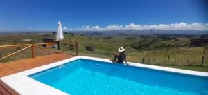 a person sitting on the edge of a swimming pool at La Autóctona in Villa Yacanto