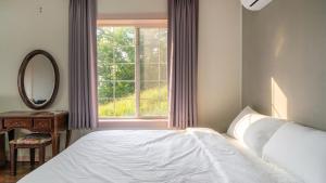 Un dormitorio con una cama y un espejo y una ventana. en Seokmodo supsokbadapunggyeong pension, en Incheon