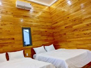 zwei Betten in einem Zimmer mit Holzwänden in der Unterkunft Homestay Hera Mang Den in Kon Plong