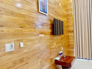 Zimmer mit einer Holzwand, einem TV und einem Tisch in der Unterkunft Homestay Hera Mang Den in Kon Plong