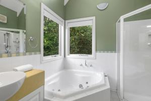 un bagno con vasca e lavandino e due finestre di Plum Retreat a Apollo Bay