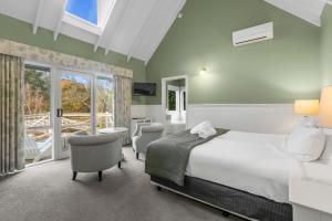 una camera da letto con un letto, sedie e una finestra di Plum Retreat a Apollo Bay