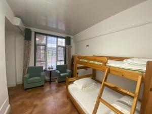 een slaapzaal met stapelbedden en een tafel en stoelen bij Half-City Homestay in Xi'an