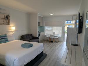 a bedroom with a bed and a kitchen with a table at Araluen Motor Lodge in Batemans Bay